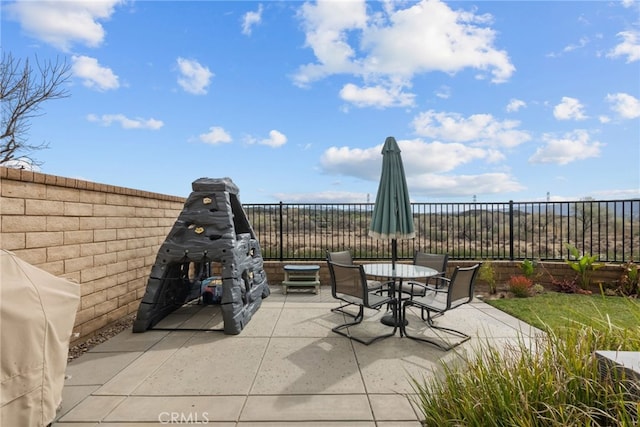 view of patio with outdoor dining space, fence, and area for grilling