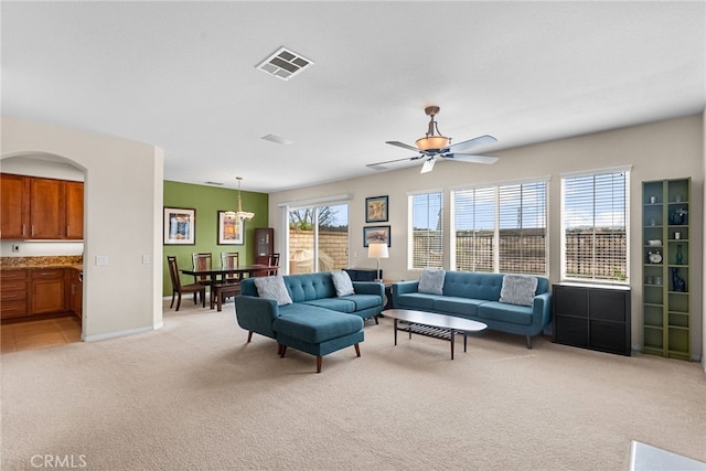 living room featuring baseboards, ceiling fan, visible vents, and light colored carpet