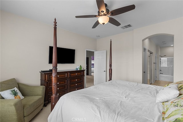 bedroom with a ceiling fan, arched walkways, visible vents, and ensuite bath