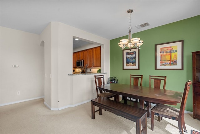 dining area featuring arched walkways, visible vents, light carpet, and an inviting chandelier