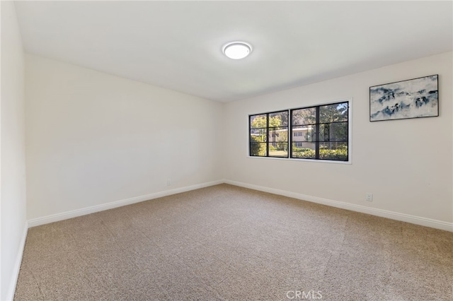 carpeted spare room featuring baseboards