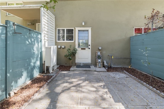 property entrance featuring a patio area, fence, and stucco siding