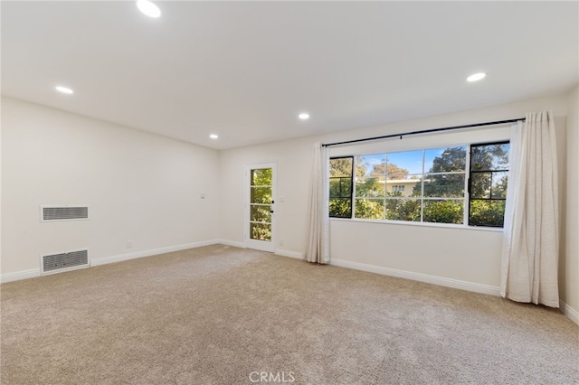 spare room with baseboards, light colored carpet, visible vents, and recessed lighting