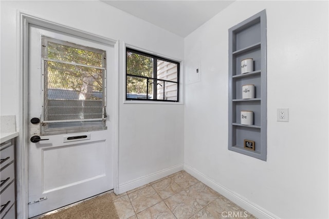 entryway featuring built in shelves and baseboards