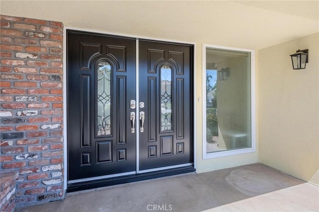 doorway to property featuring brick siding and stucco siding