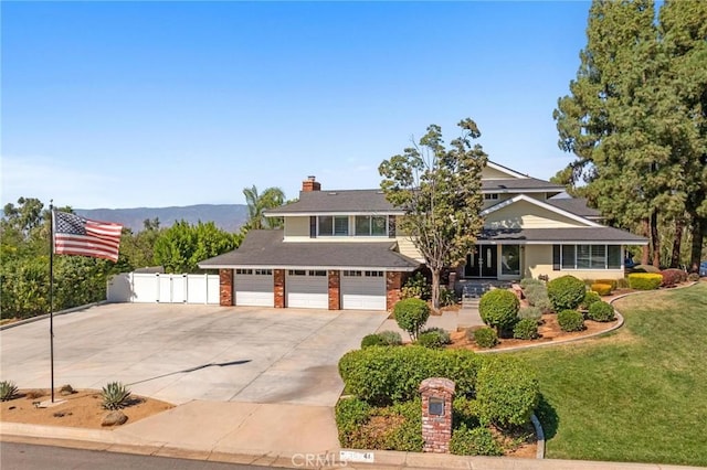 view of front facade featuring concrete driveway, a chimney, a gate, fence, and a front lawn