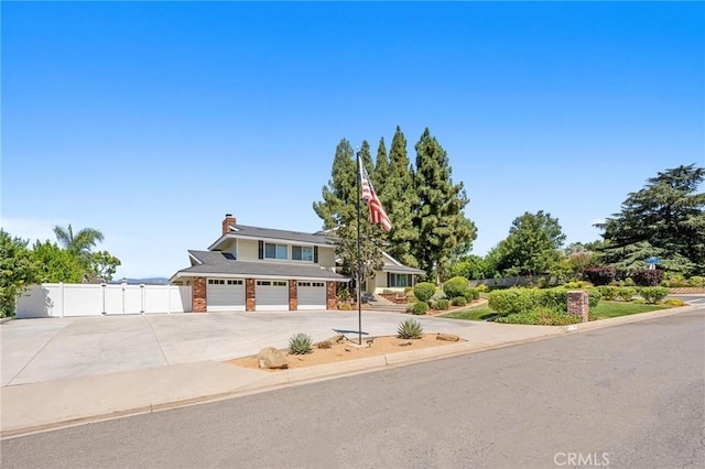 view of front of house with a chimney, a gate, fence, and concrete driveway