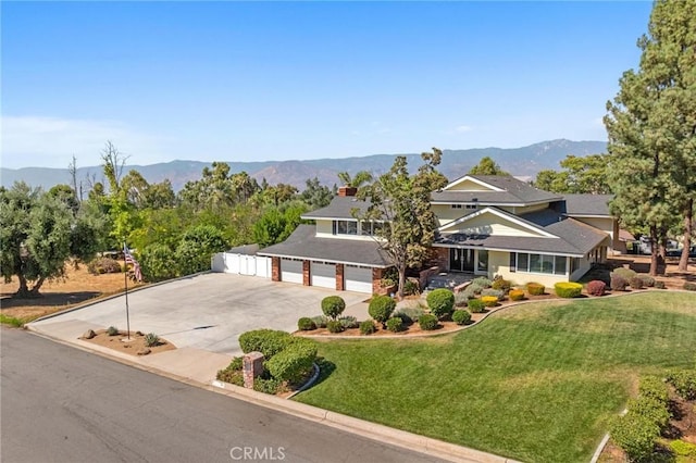 view of front of property featuring a garage, a mountain view, a front lawn, and concrete driveway