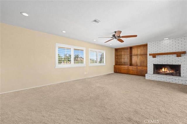 unfurnished living room featuring carpet floors, a brick fireplace, visible vents, and a ceiling fan