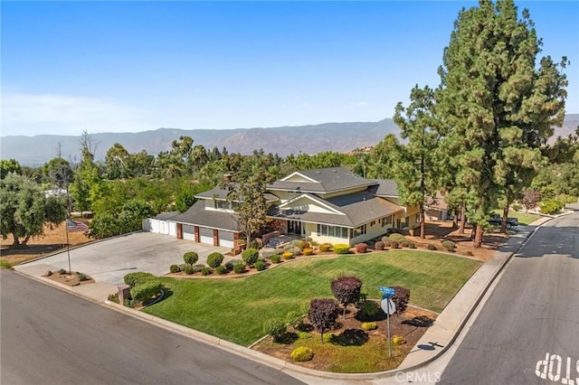 view of front of property with a garage, concrete driveway, a front yard, and a mountain view