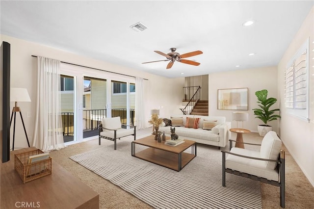 carpeted living room with a ceiling fan, recessed lighting, visible vents, and stairway