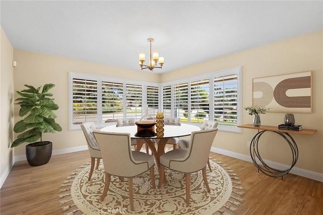 dining space with a chandelier, light wood-style flooring, and baseboards