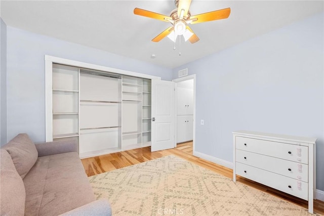 bedroom with a closet, visible vents, baseboards, and wood finished floors