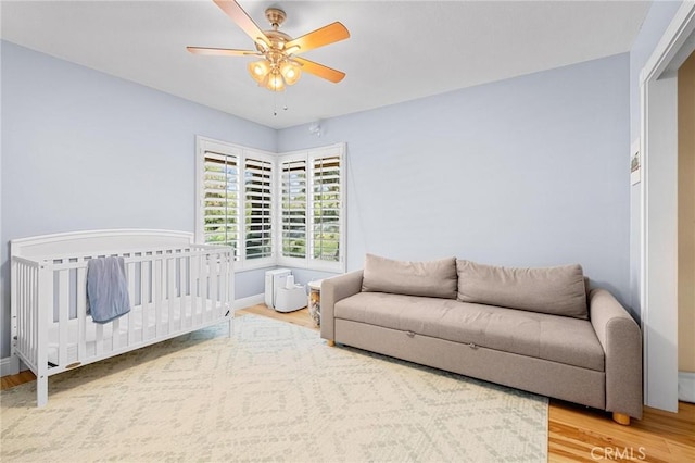 bedroom with light wood finished floors, a ceiling fan, and baseboards