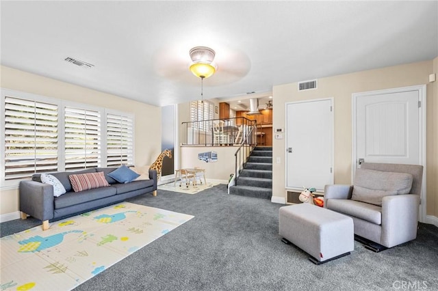 carpeted living room featuring stairs, visible vents, and baseboards