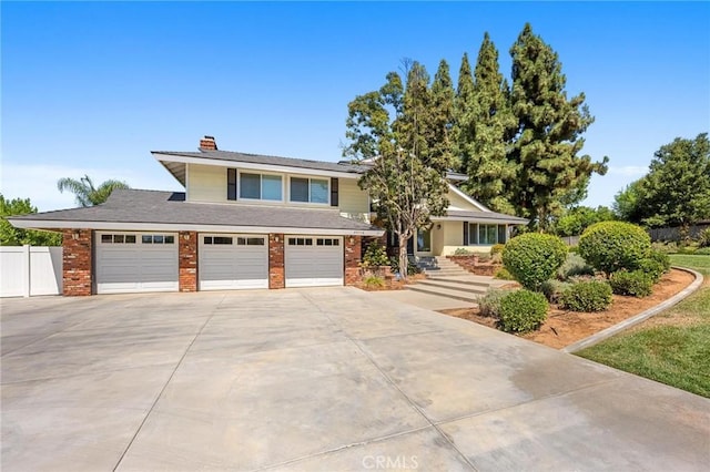 view of front facade featuring a garage, concrete driveway, a chimney, fence, and brick siding