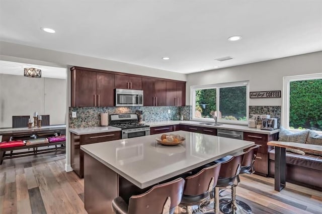 kitchen with tasteful backsplash, appliances with stainless steel finishes, light countertops, and a kitchen breakfast bar