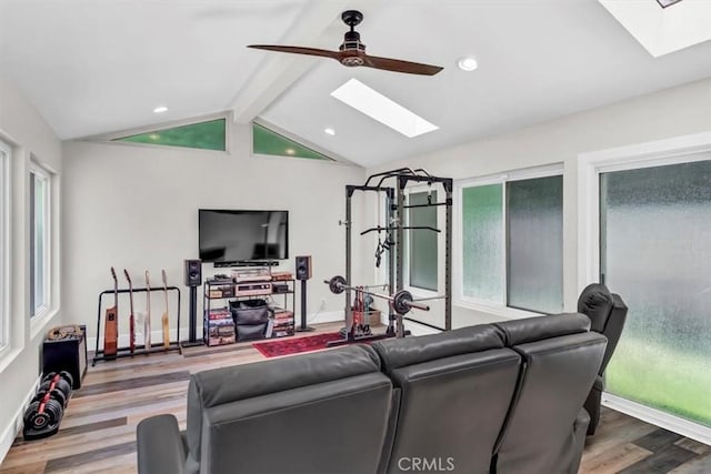 living area with ceiling fan, vaulted ceiling with skylight, recessed lighting, wood finished floors, and baseboards