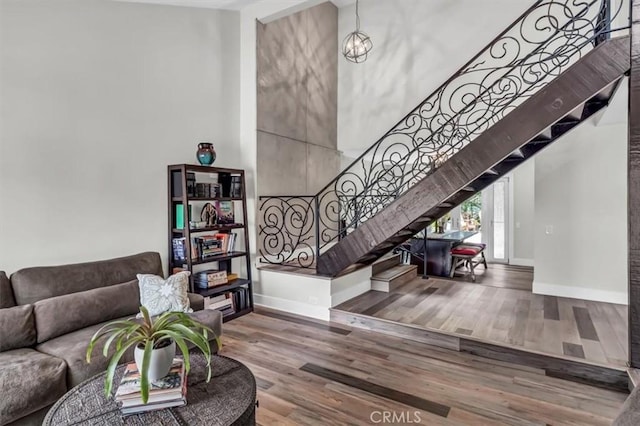 living area featuring baseboards, a high ceiling, stairway, and wood finished floors