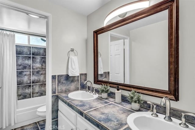 bathroom with double vanity, shower / bath combo with shower curtain, a sink, and toilet