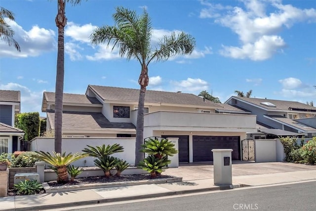 view of front of home with a garage, fence, concrete driveway, a gate, and stucco siding