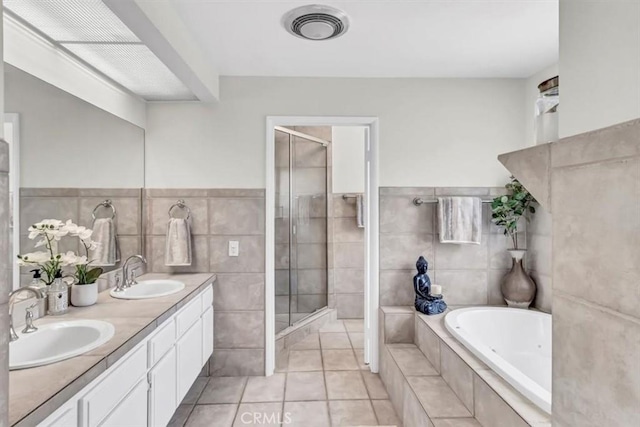 bathroom featuring a stall shower, visible vents, a sink, and a garden tub