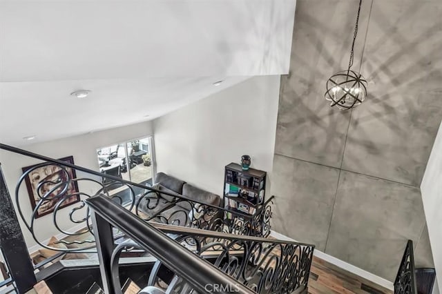 stairs with a chandelier, wood finished floors, and baseboards