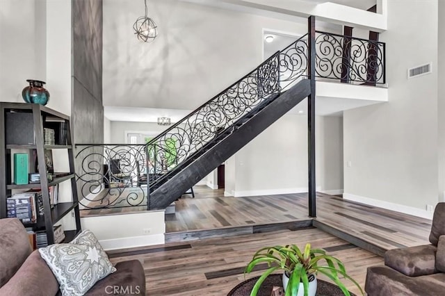 stairway featuring a high ceiling, wood finished floors, visible vents, and baseboards