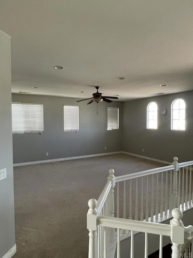 spare room featuring carpet, baseboards, ceiling fan, and a textured ceiling