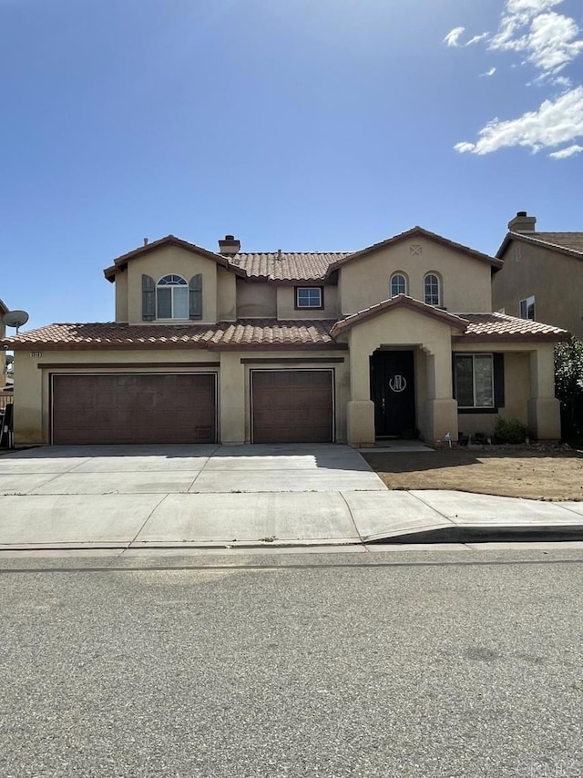 mediterranean / spanish-style home with a garage, driveway, a tile roof, and stucco siding