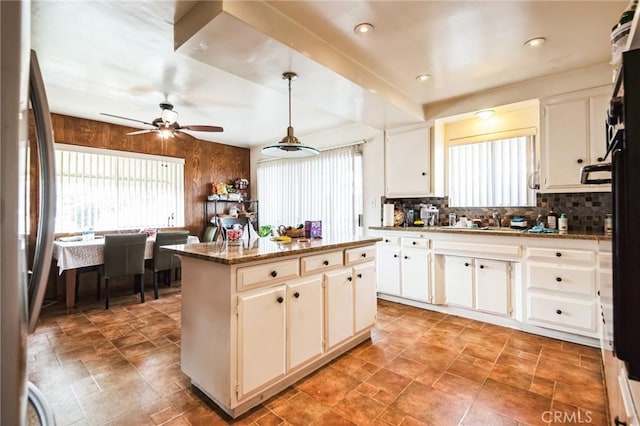 kitchen featuring a wealth of natural light, backsplash, a kitchen island, and freestanding refrigerator