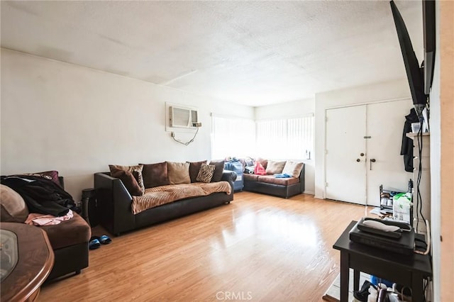 living area featuring a wall unit AC, a textured ceiling, and wood finished floors