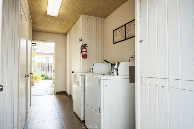 shared laundry area featuring baseboards, separate washer and dryer, and a textured ceiling