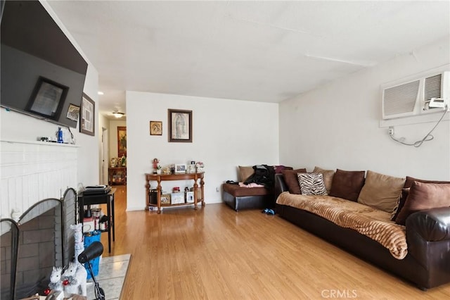 living area with a fireplace, wood finished floors, and a wall mounted air conditioner