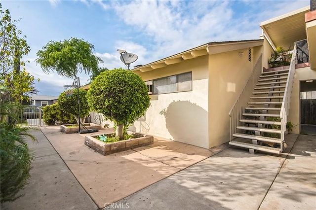 exterior space with stucco siding, fence, a patio, and stairs