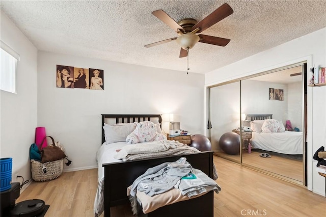 bedroom with a textured ceiling, a closet, wood finished floors, and a ceiling fan