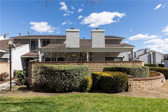 rear view of property with a chimney and stucco siding