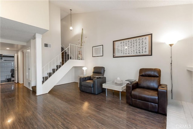 living area featuring stairs, high vaulted ceiling, wood finished floors, and visible vents