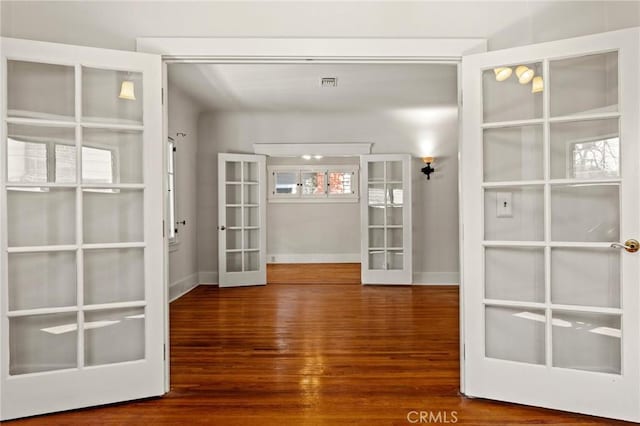 interior space with wood finished floors, french doors, visible vents, and baseboards