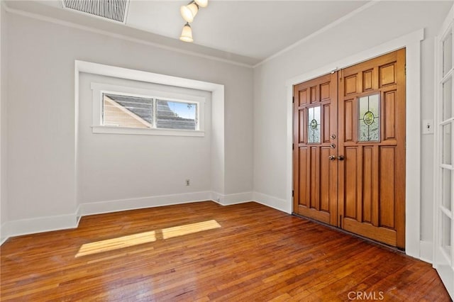 entryway with visible vents, crown molding, baseboards, and hardwood / wood-style floors