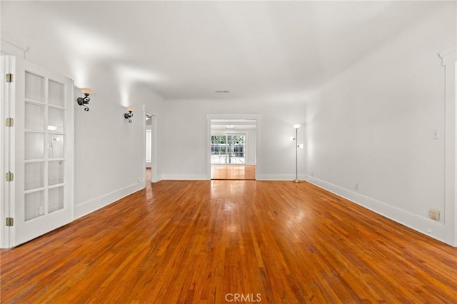 empty room featuring visible vents, baseboards, and wood finished floors