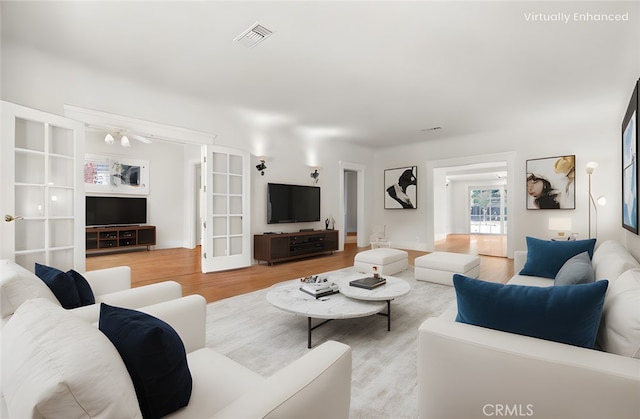 living room featuring light wood-type flooring, french doors, and visible vents