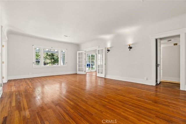 unfurnished living room with french doors, baseboards, visible vents, and hardwood / wood-style flooring