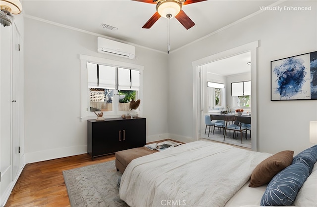 bedroom featuring visible vents, crown molding, baseboards, an AC wall unit, and wood finished floors