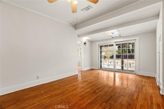 empty room with visible vents, baseboards, wood finished floors, and crown molding