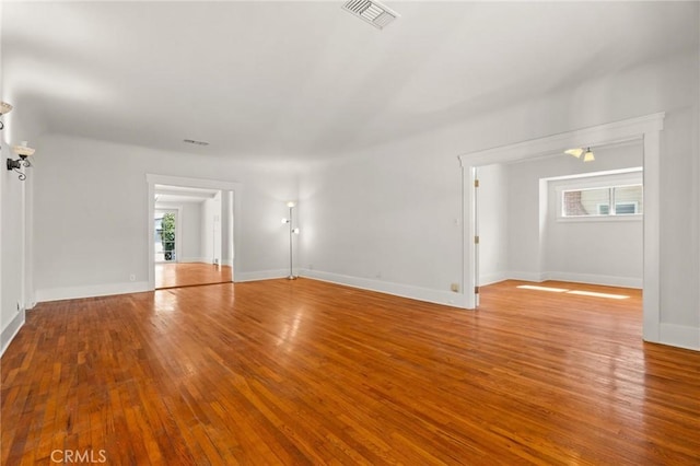 unfurnished room featuring hardwood / wood-style flooring, baseboards, and visible vents