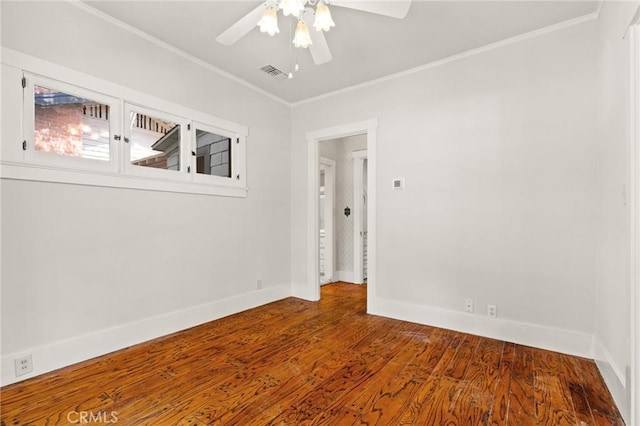 spare room featuring visible vents, crown molding, baseboards, wood finished floors, and a ceiling fan