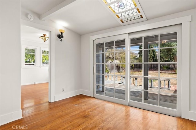 entryway featuring beam ceiling, baseboards, and wood finished floors