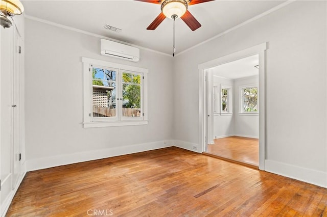 unfurnished room with crown molding, a wealth of natural light, light wood finished floors, and a wall mounted air conditioner