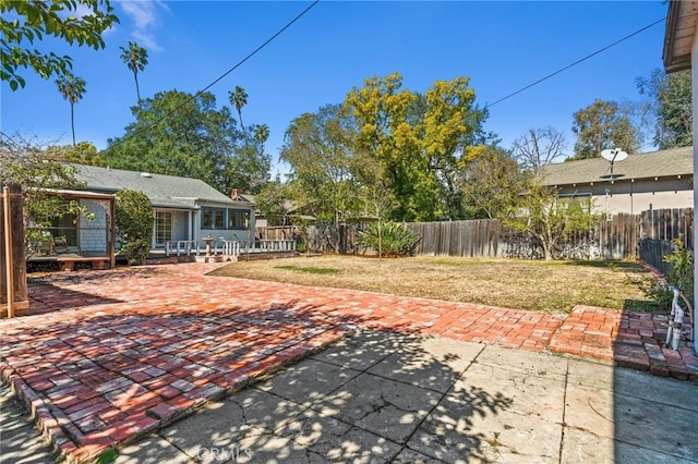 exterior space featuring a wooden deck, a patio, and a fenced backyard